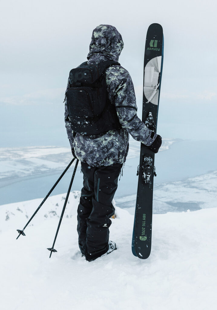 A person standing on a snowy mountain and holding skis in their hand.